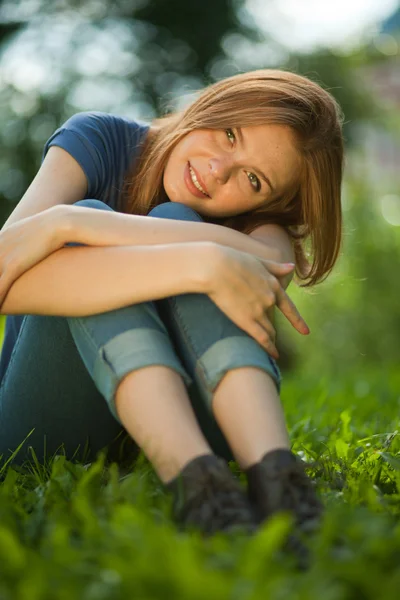 Krásná rusovlasá dívka sedící na trávě — Stock fotografie