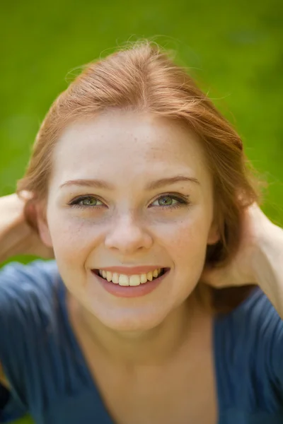 美丽的红发微笑女孩的树叶背景上 — 图库照片