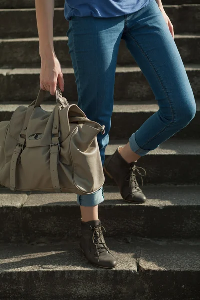 stock image Feet girl holding a bag on the stairs in jeans