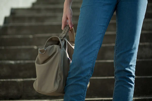 stock image Feet girl holding a bag on the stairs in jeans