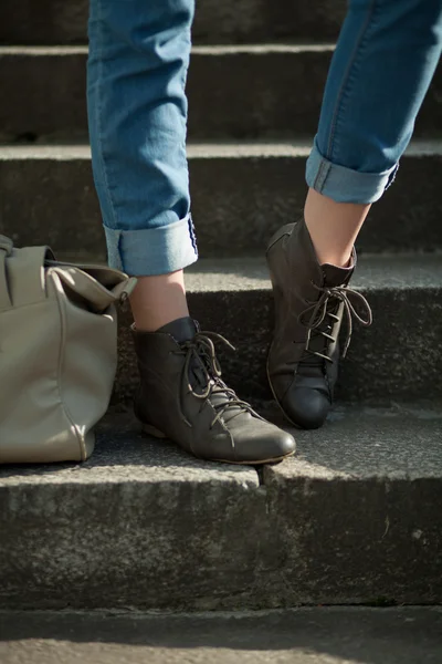 Fötter flicka håller en väska på trappan i jeans — Stockfoto