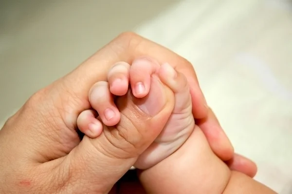 Pulgar adulto en brazos del bebé — Foto de Stock