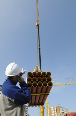 Worker directing heavy crane load clipart