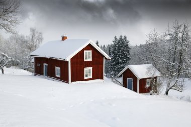 Red cottage in snowy landscape clipart