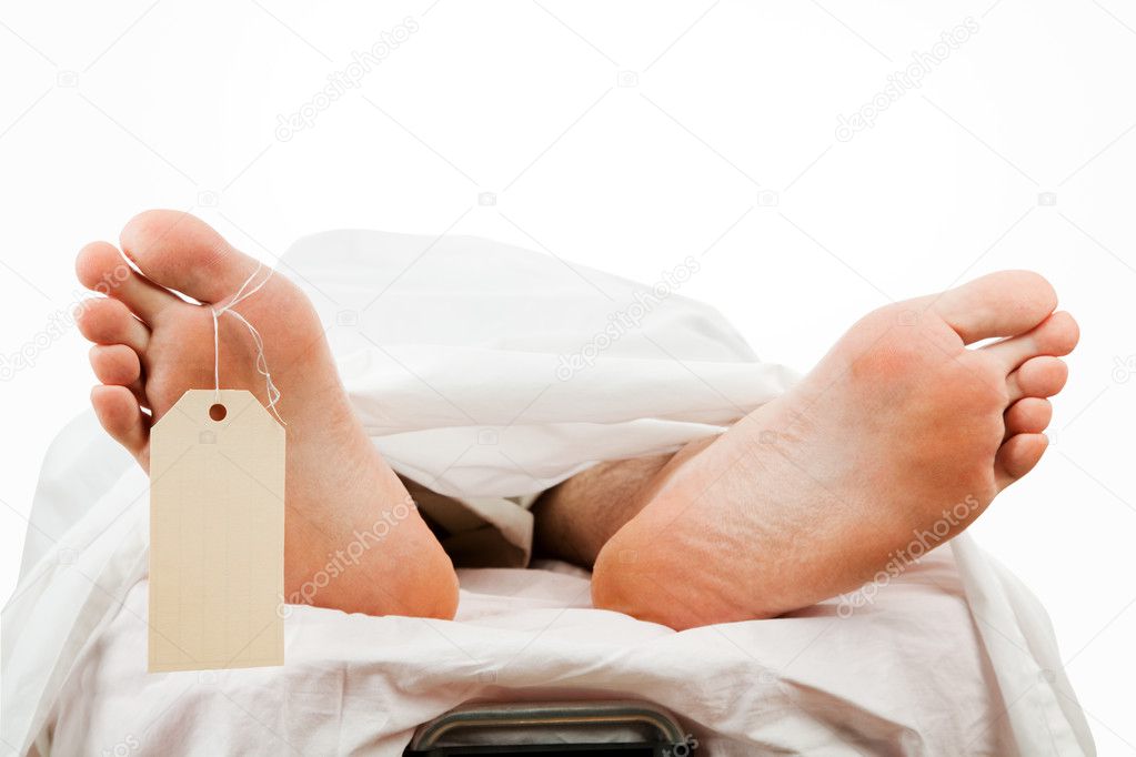 Closeup of a corpse on a gurney wearing a toe tag. Isolated with clipping path.