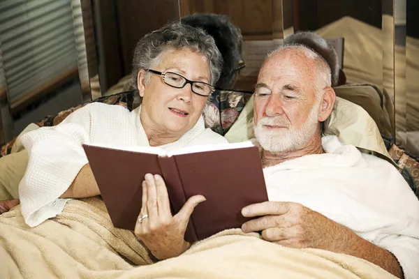 Starší pár čtení v posteli — Stock fotografie