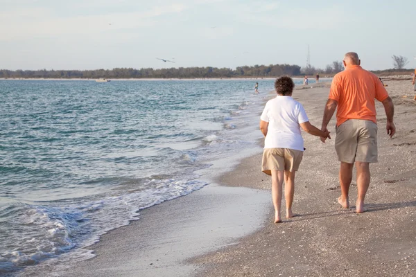 Senioren wandelen op het strand — Stockfoto
