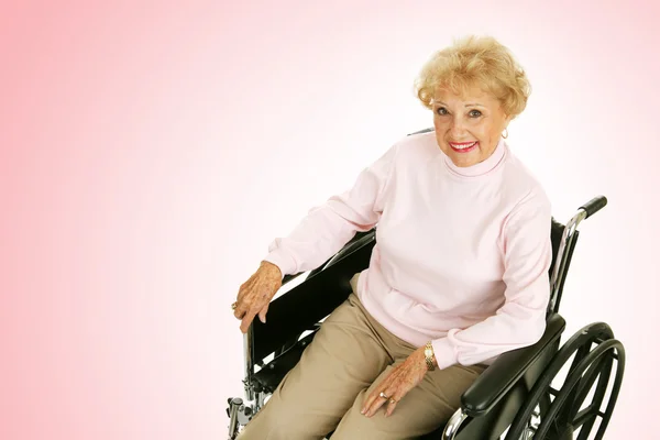 Anziana signora in sedia a rotelle rosa — Foto Stock
