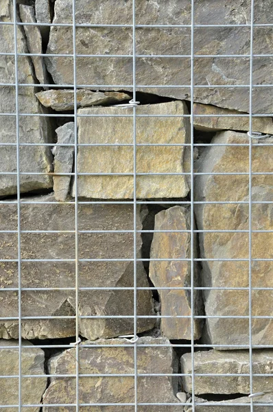 Stone wall texture in the wire reinforcement — Stock Photo, Image