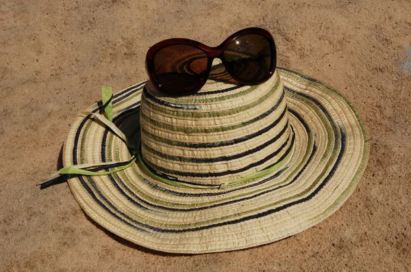 Solhatt och solglasögon i sanden. — Stockfoto