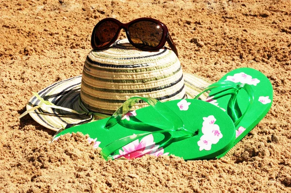 Güneş şapkası, güneş gözlüğü ve kum üzerinde parmak arası terlik — Stok fotoğraf