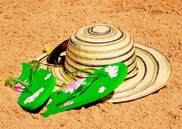 Chapéu de sol, óculos de sol e chinelos na areia — Fotografia de Stock