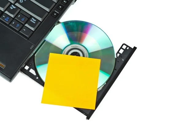 Nahaufnahme einer DVD in einem Laptop-Tray und Post-it — Stockfoto