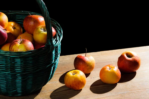 Apples in basket on old plank on black background — Stock Photo, Image