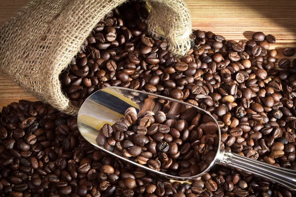 Saco con granos de café sobre tabla vieja — Foto de Stock
