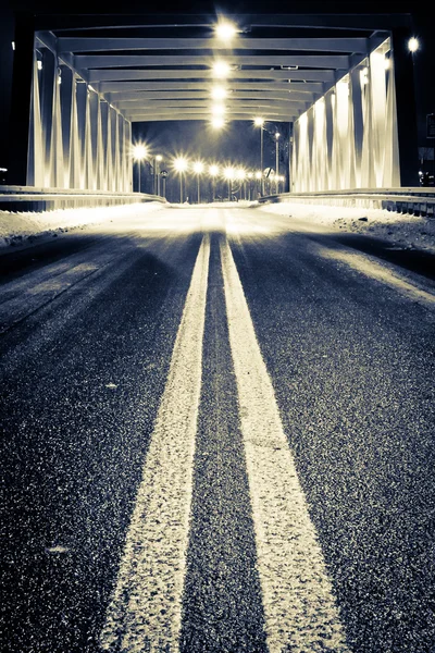 stock image Road by illuminated bridge at night in winter