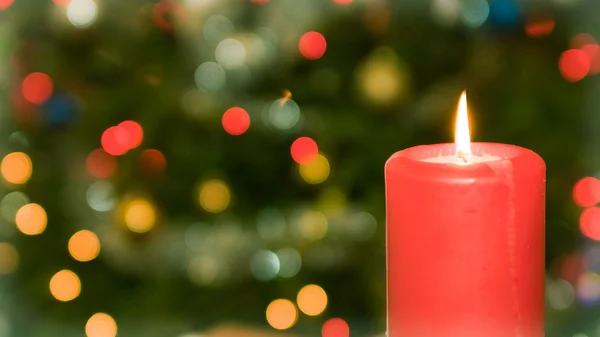 Свеча на фоне рождественской елки — стоковое фото