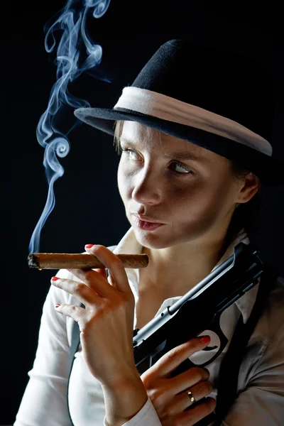 stock image Woman in black hat with smoking cigar and gun black background