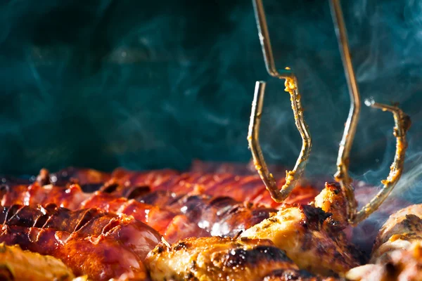 Sausage and Chicken in barbecue with tongs — Stock Photo, Image