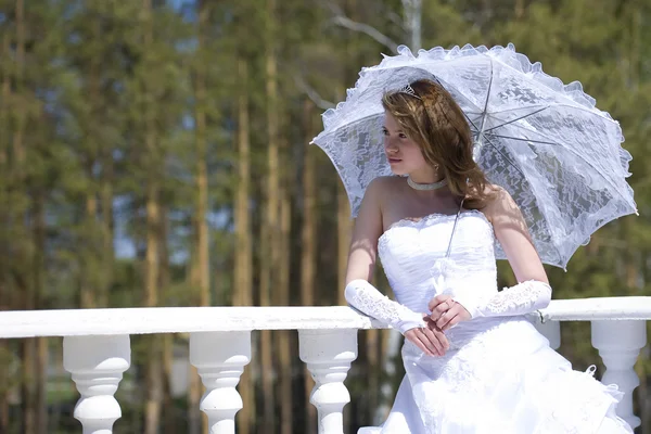 Bruden med ett paraply i en solig dag — Stockfoto