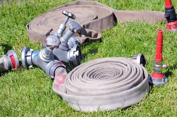 Valves and fire hoses in action on grass — Stock Photo, Image