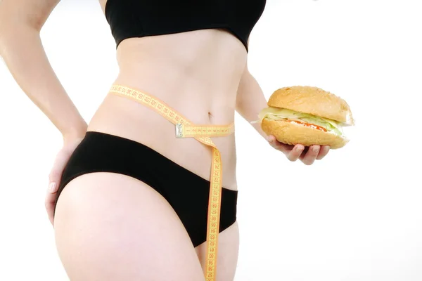 Woman measuring waist measuring tape and hamburger — Stock Photo, Image