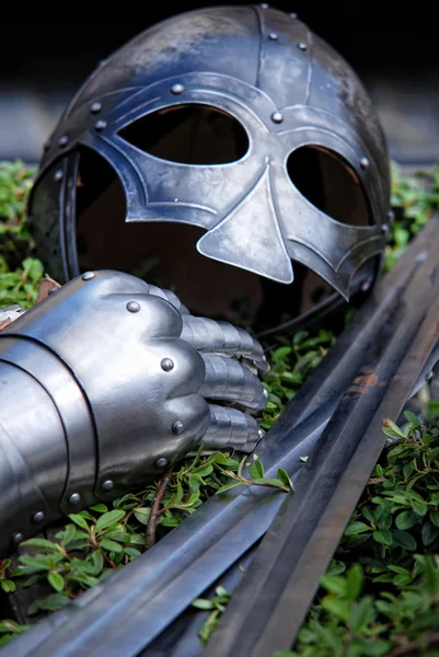 Металлический рыцарский шлем, меч и перчатки — стоковое фото