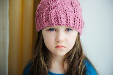 Pembe örgü şapkalı sevimli üzgün kız.