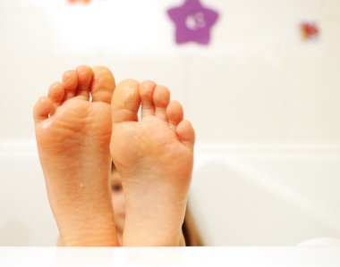 Little girl feet covered with water in the bathtub clipart