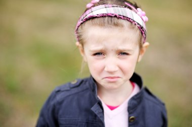 Cute child girl makes upset weepy face clipart