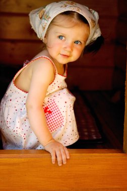 Adorable baby girl hides inside a playground house clipart