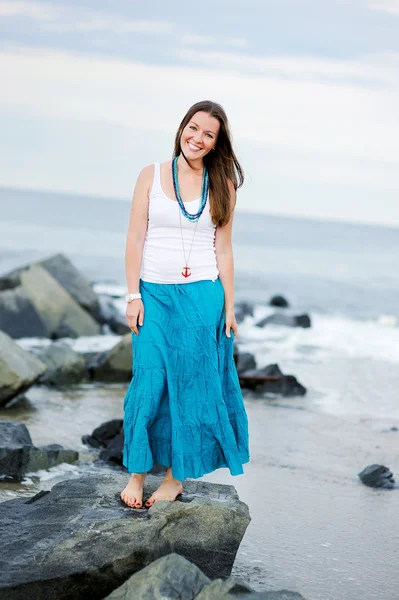 Belle femme souriante se tient contre l'océan — Photo