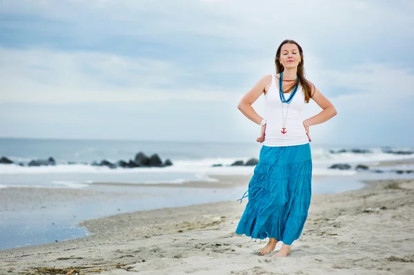 stock image Beautiful young woman stands against ocean