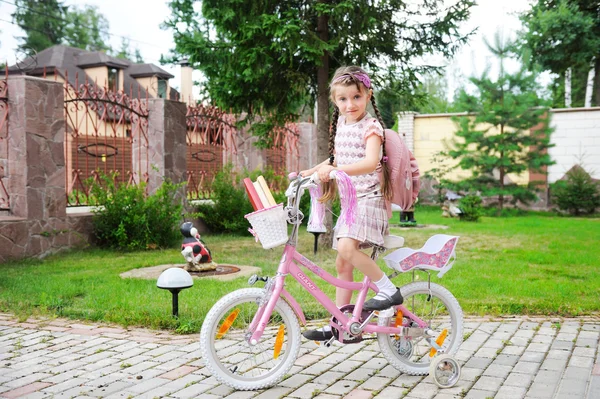 Menina da escola jovem com mochila rosa em uma bicicleta — Fotografia de Stock