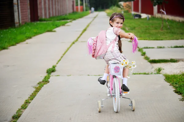 Jonge school meisje met roze rugzak op een fiets — Stockfoto