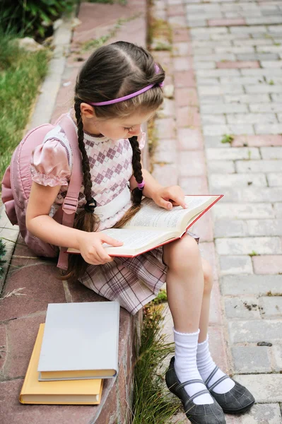 Giovane ragazza con zaino legge in attesa di scuola — Foto Stock