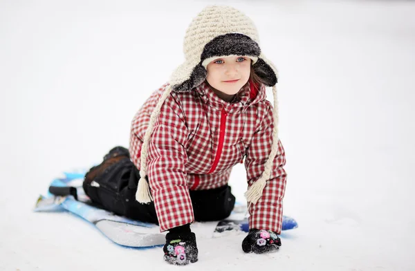 Очаровательная девочка катается на санках по снегу на тарелке — стоковое фото