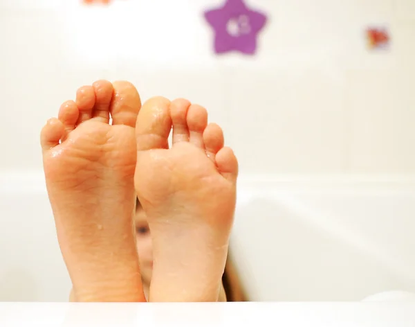 Pequena menina pés cobertos com água na banheira — Fotografia de Stock