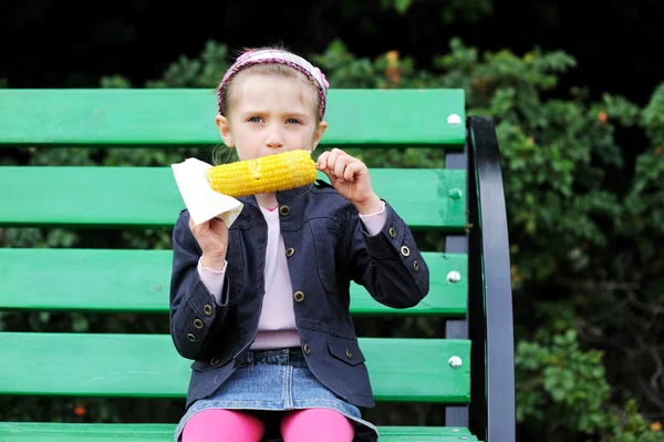 Mooi kind meisje een gekookte maïs buiten eten — Stockfoto
