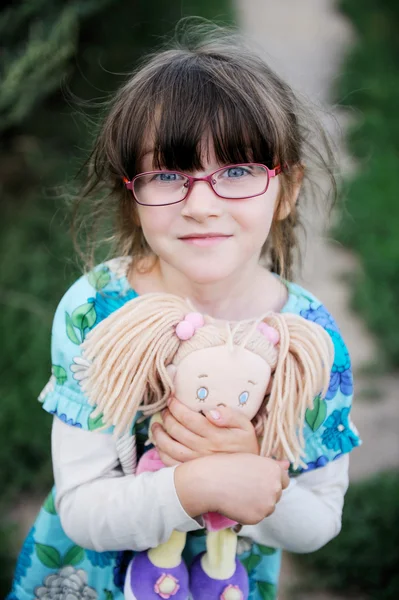 Adorabile ragazza bruna bambino in abito estivo blu abbraccia bambola bambino — Foto Stock