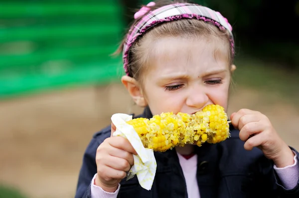 Κορίτσι όμορφο παιδί που τρώει ένα βρασμένο καλαμπόκι σε εξωτερικούς χώρους — Φωτογραφία Αρχείου