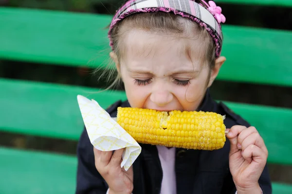 Jolie enfant fille manger un maïs bouilli à l'extérieur — Photo