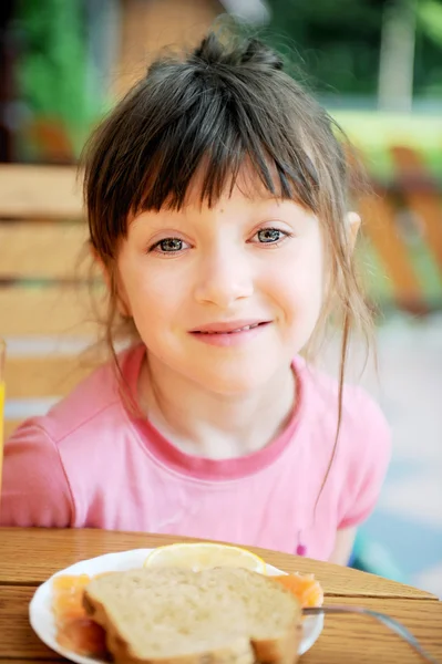 Cute child girl has a breakfast outdoors — Stock Photo, Image