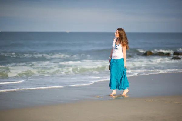 Stock image Beautiful young woman walks along the ocean