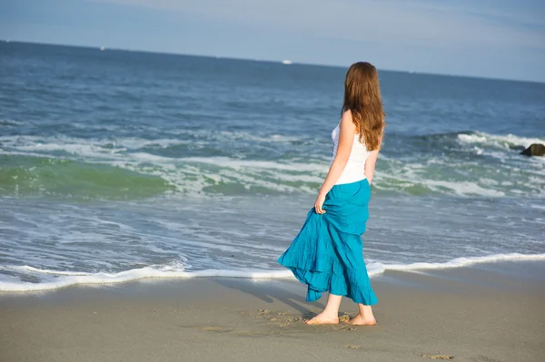 stock image Beautiful young woman walks along the ocean