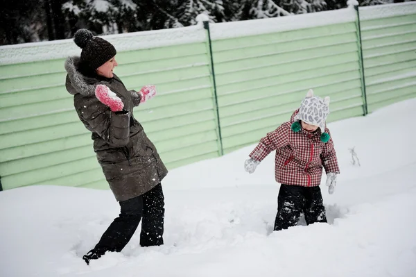 Молодая мать и дочь веселятся в снегу — стоковое фото