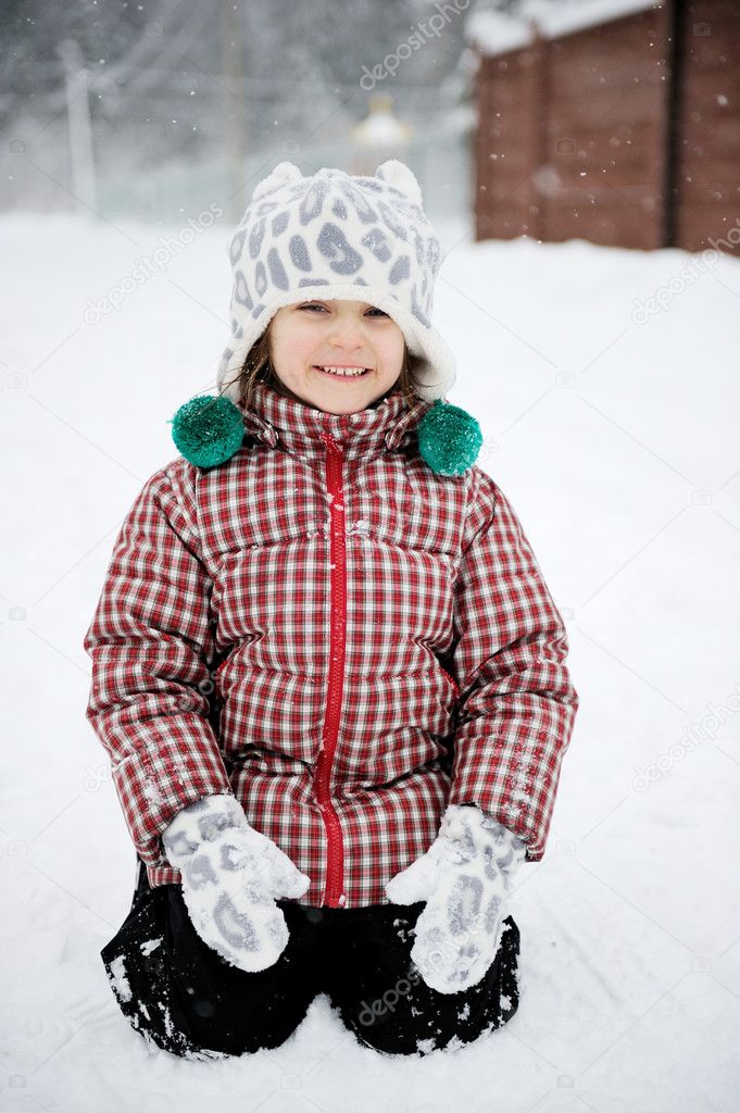 Adorable smiling child girl has fun in the snow