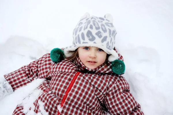 Bedårande barn flicka ligger i snön — Stockfoto