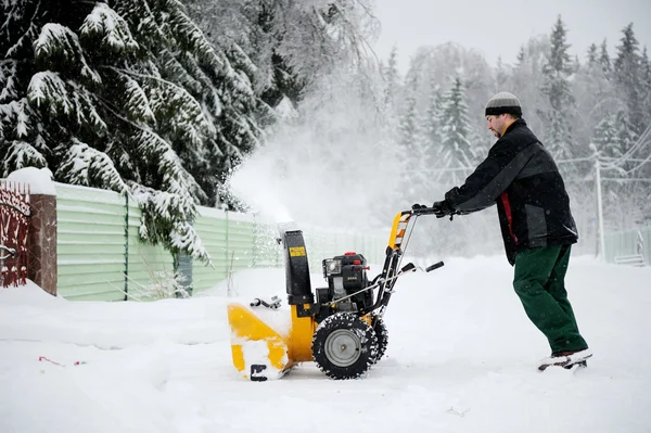 Un hombre operando soplador de nieve en invierno — Foto de Stock