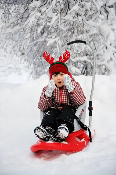 Adorable child girl in horned hat sled in snow — Stock Photo, Image